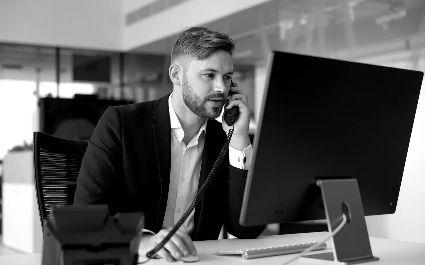 Black-and-white administrative professional handling phone support at a desk